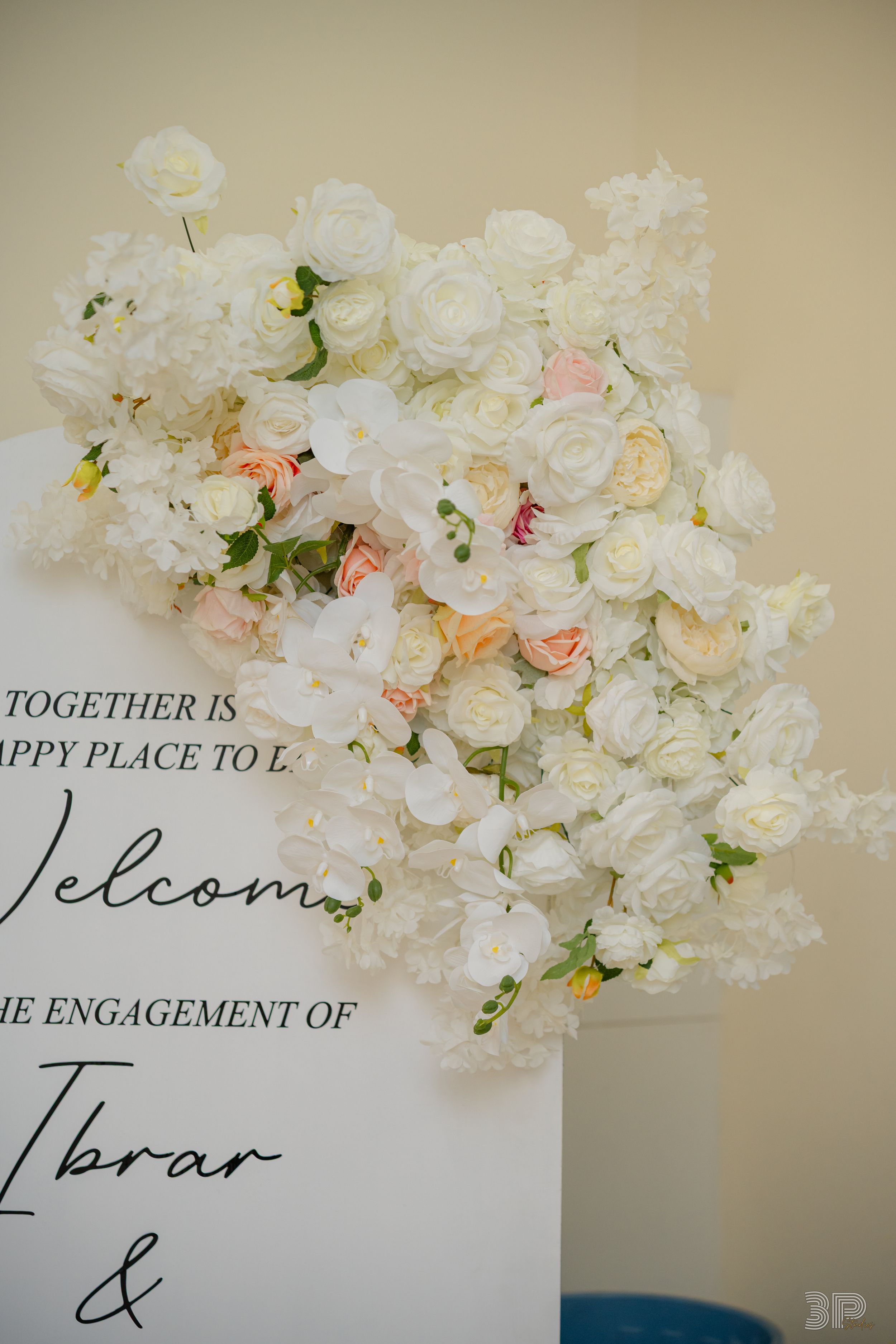 White floral wedding signage with elegant calligraphy text decorated with roses and peonies.