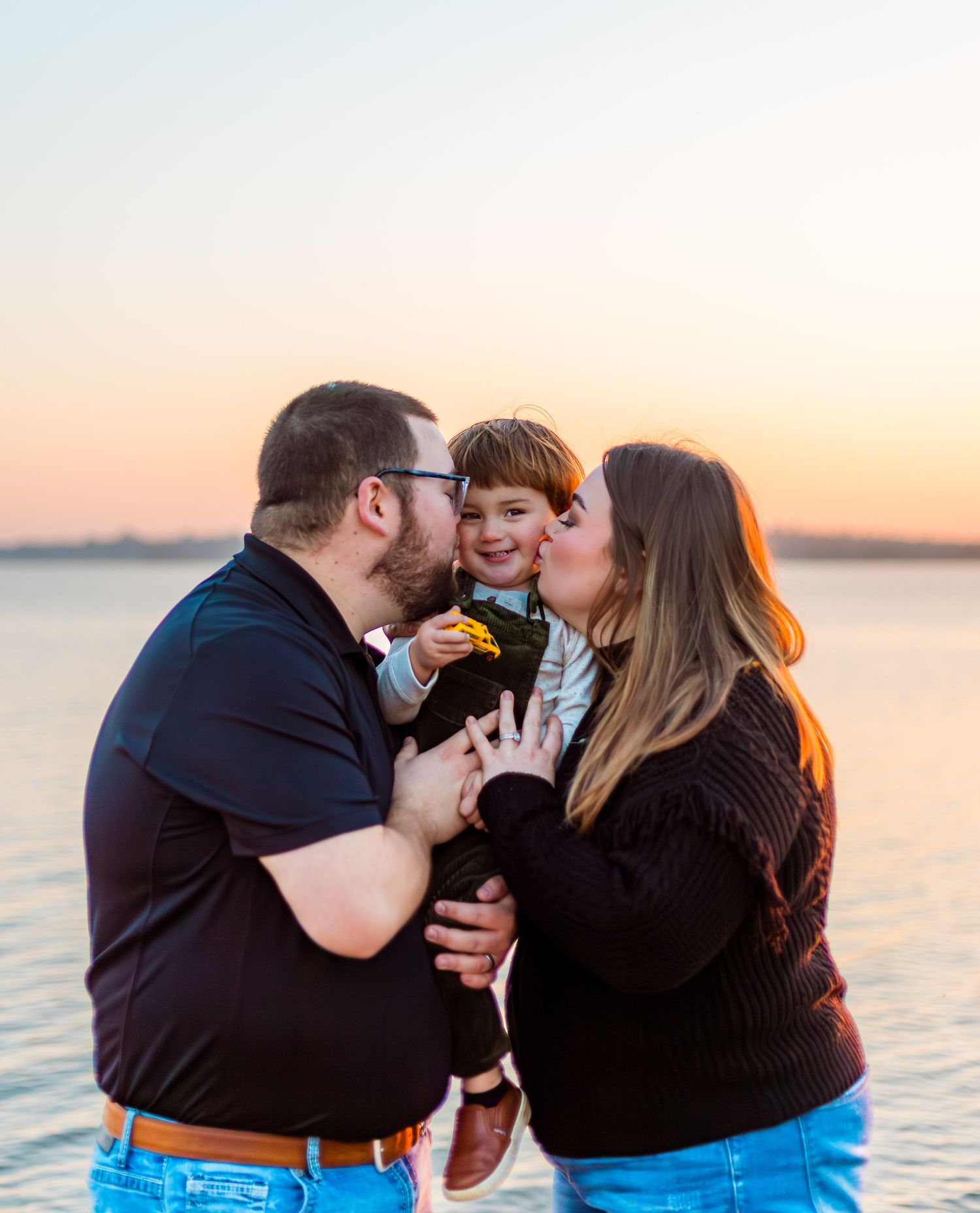 Family shares tender moment together during golden sunset by the waterfront.