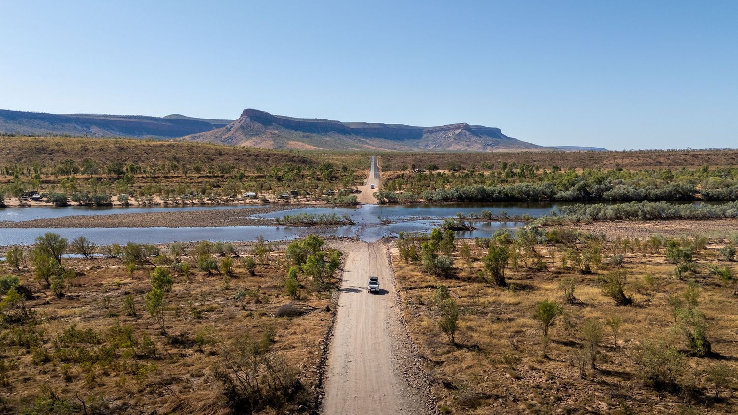 Aerial view of a dirt road crossing a river in remote outback Australia.
