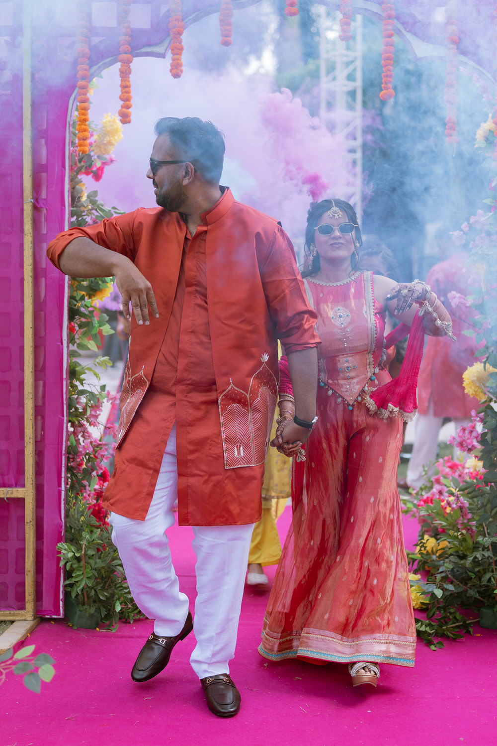 Colorful smoke effects and traditional decorations create a festive atmosphere at an Indian cultural celebration.