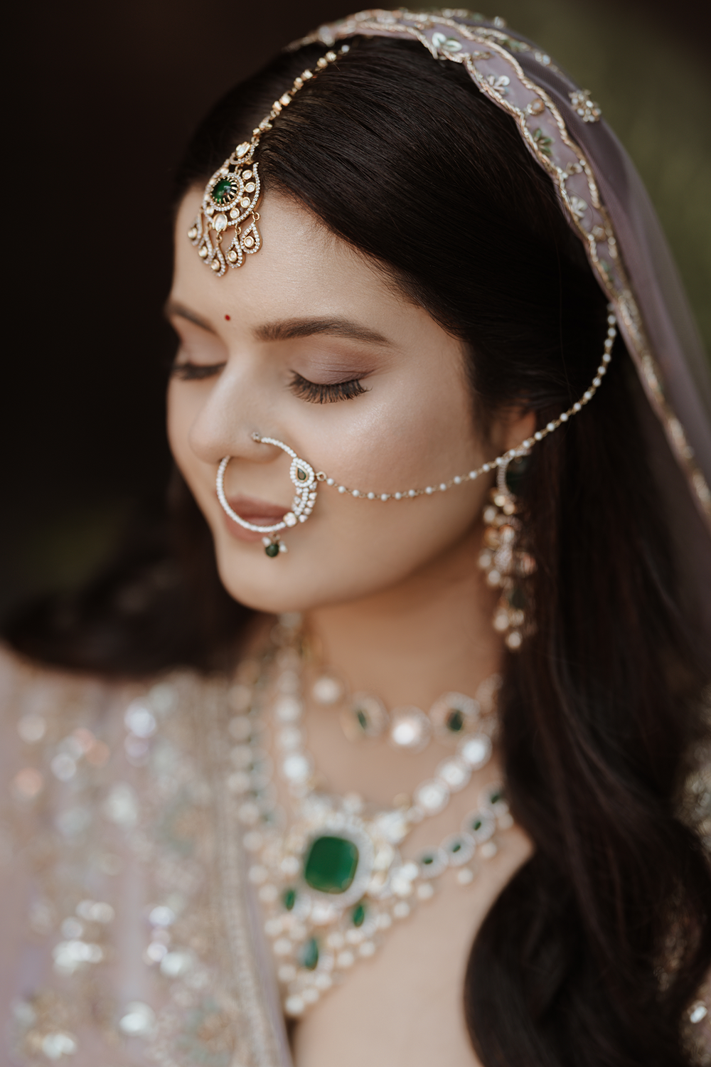 Close-up details of ornate bridal jewelry featuring emerald stones, pearls, and delicate chains in traditional South Asian style.