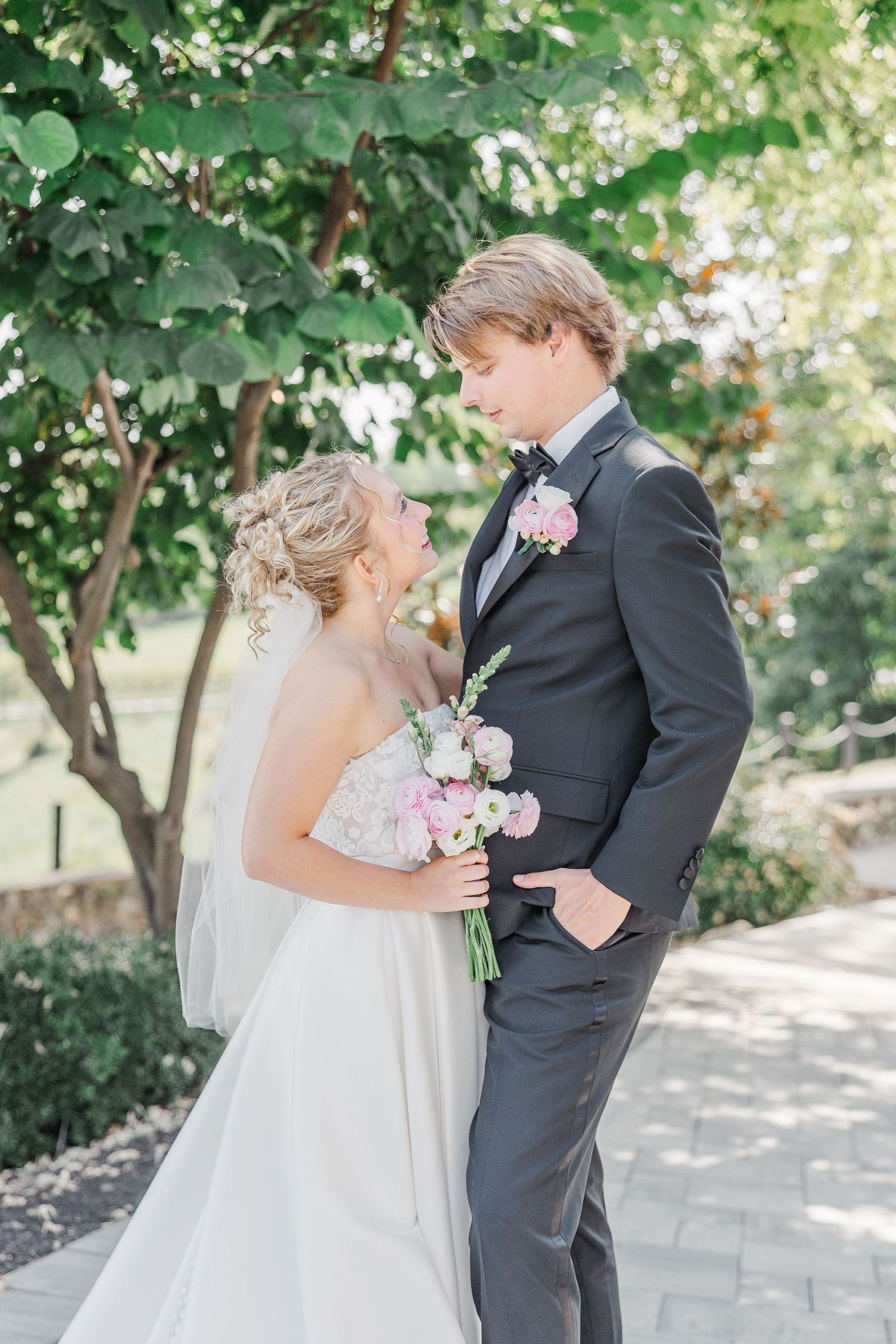 A sweet wedding moment captured on a garden path with natural greenery.
