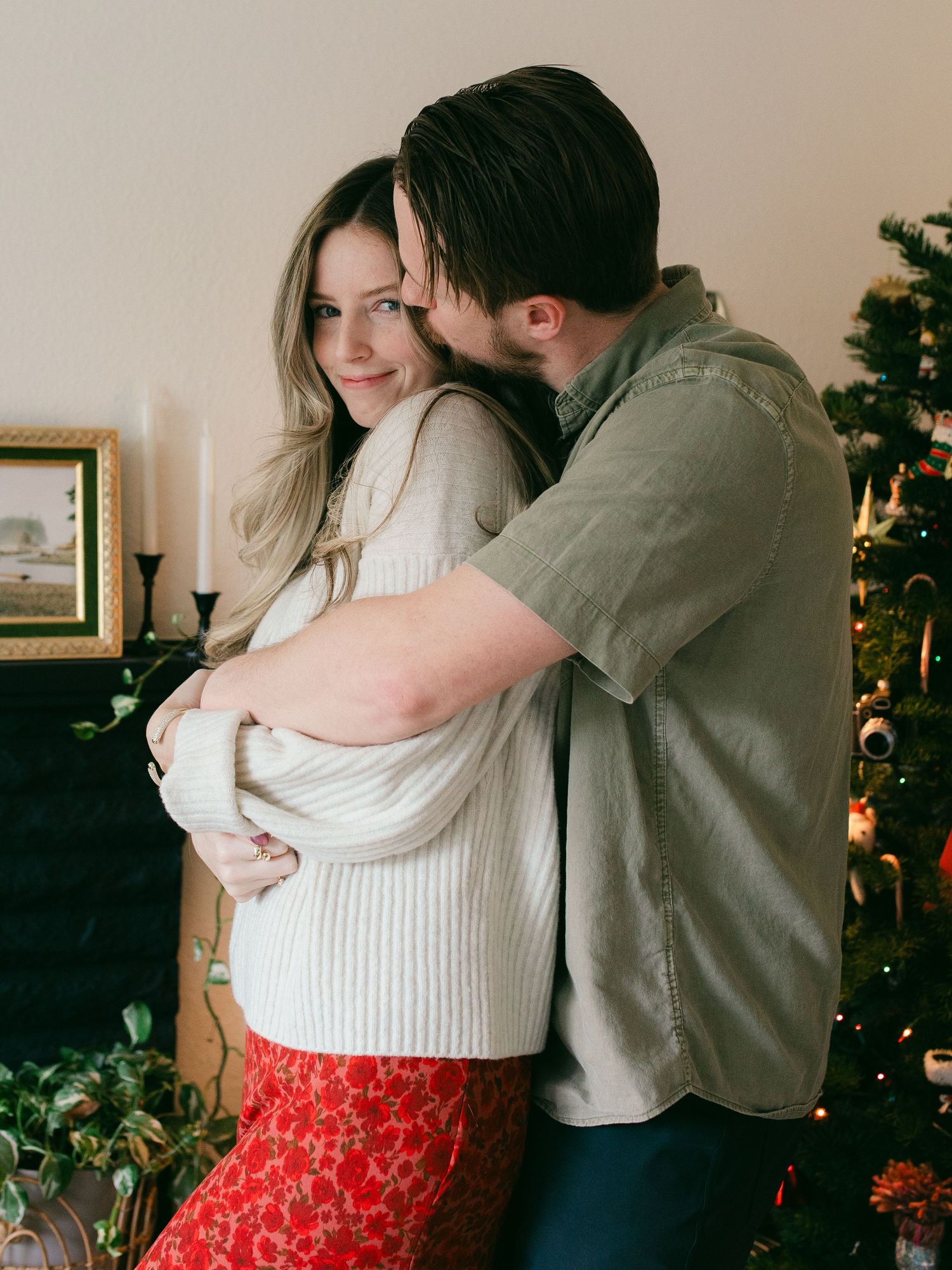 A couple shares a romantic moment by a Christmas tree, showing affection in a series of progressive shots.