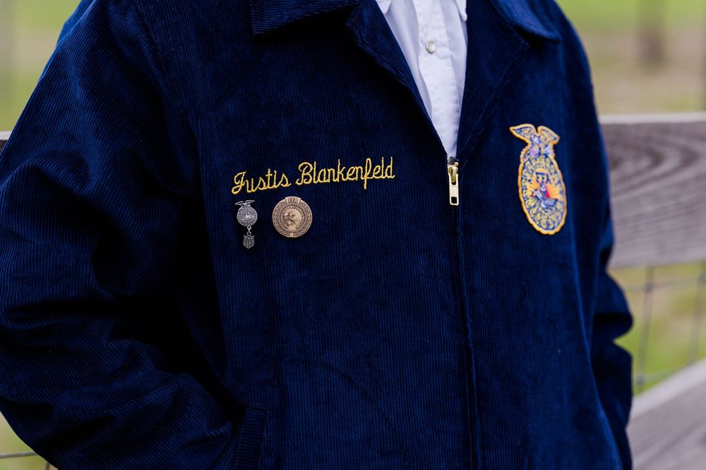 A close-up view of navy blue FFA jackets with corduroy texture and gold embroidered patches.