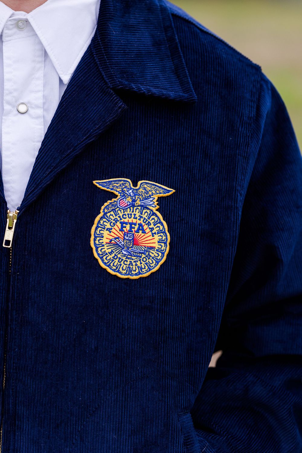 Close-up detail shots of an FFA emblem patch on a navy blue jacket.
