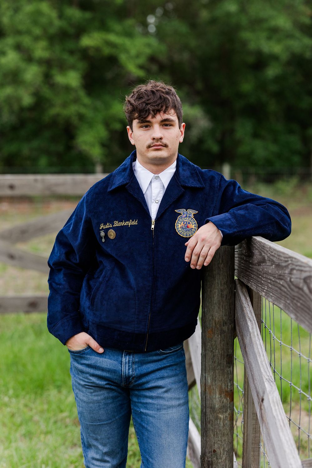 Multiple shots of someone wearing a blue FFA jacket leaning on a wooden fence in a pastoral setting.