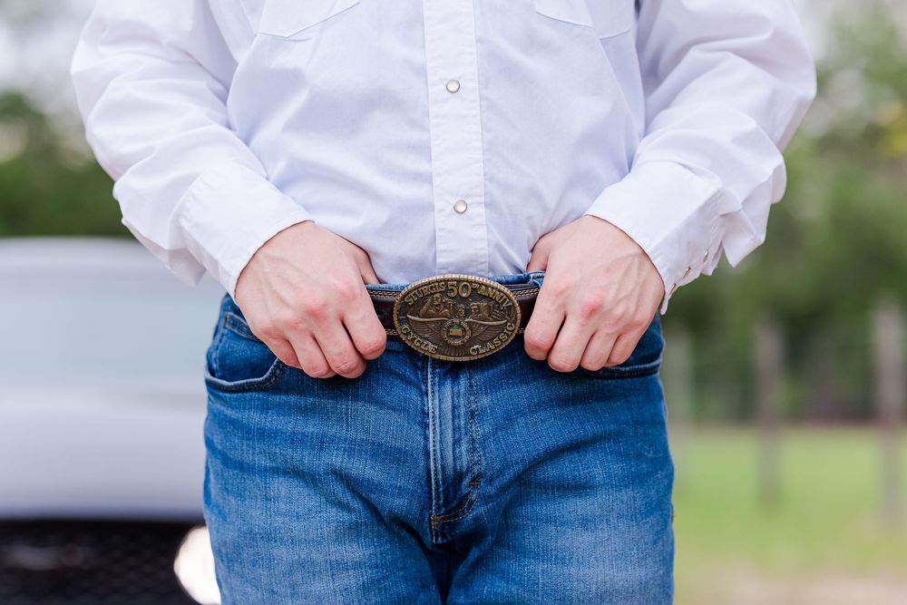 Person wearing blue jeans and white button-up shirt standing outdoors in casual pose.