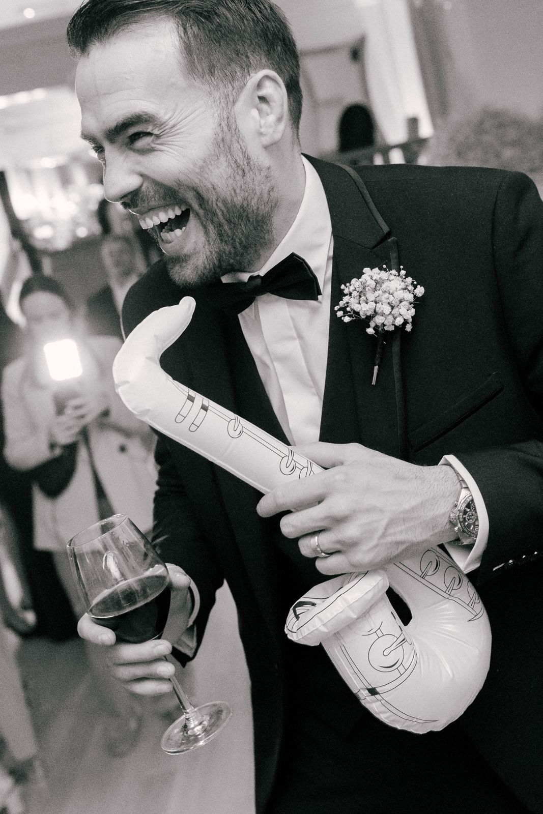 Black and white photo series showing someone in a tuxedo laughing while holding a champagne bottle at a formal event.