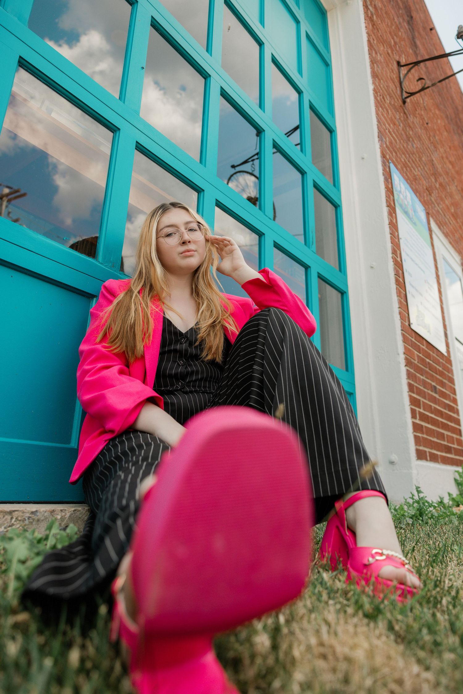 Fashion shots against turquoise windows wearing pink and black pinstripe outfit.