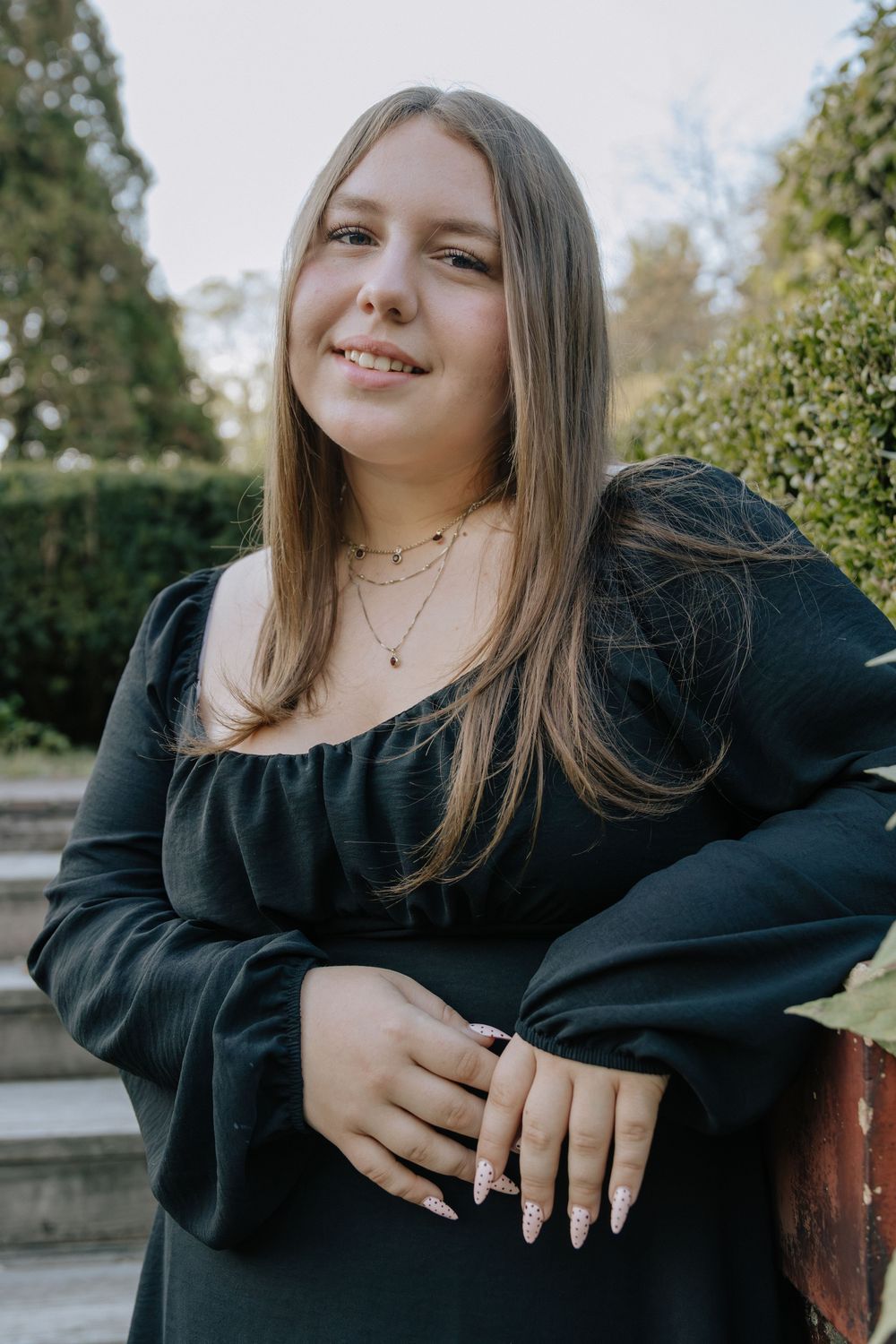 A series of casual poses captured outdoors featuring someone in a black long-sleeve dress.