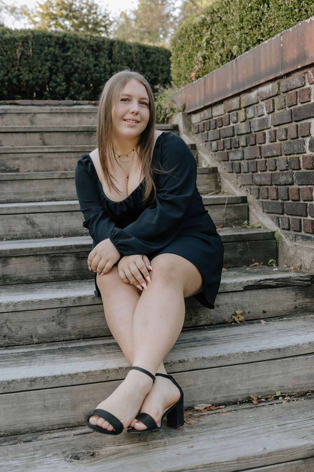 Relaxed outdoor photoshoot on weathered wooden steps near a brick wall.