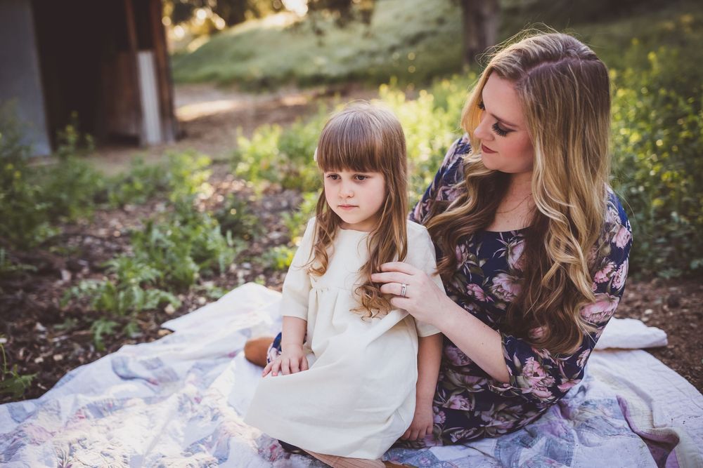 Family portrait session in a natural outdoor setting with soft lighting and floral dresses.