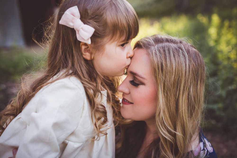 Intimate family portrait session shows gentle embraces between parent and child in garden setting.