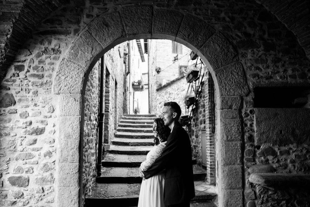 A romantic black and white photograph under a stone archway in an Italian alleyway with steps ascending in the background in Garfagnana.