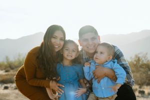 A happy family of four poses together outdoors in the desert during golden hour.