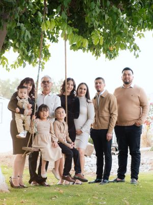 Multi-generational family group portrait under a tree wearing coordinated neutral colors.