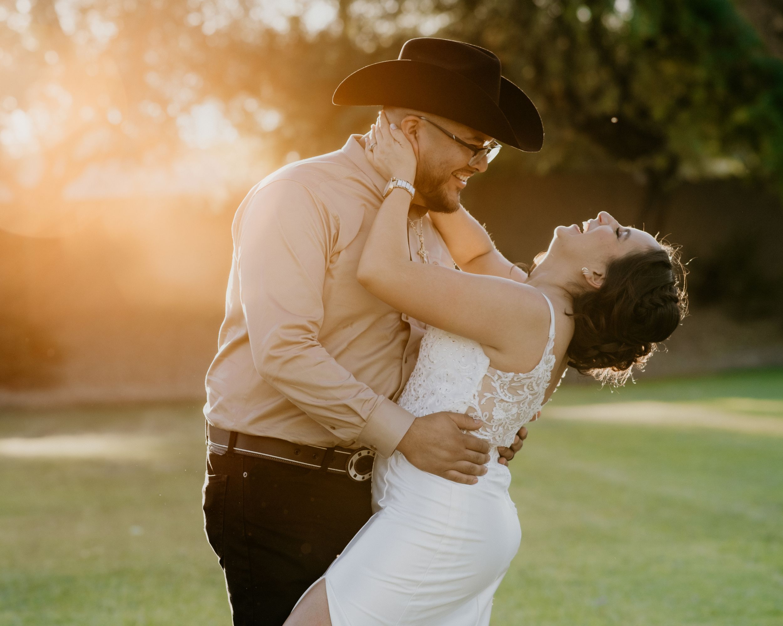 A romantic sunset wedding photo of a couple dancing in western vaquero attire.