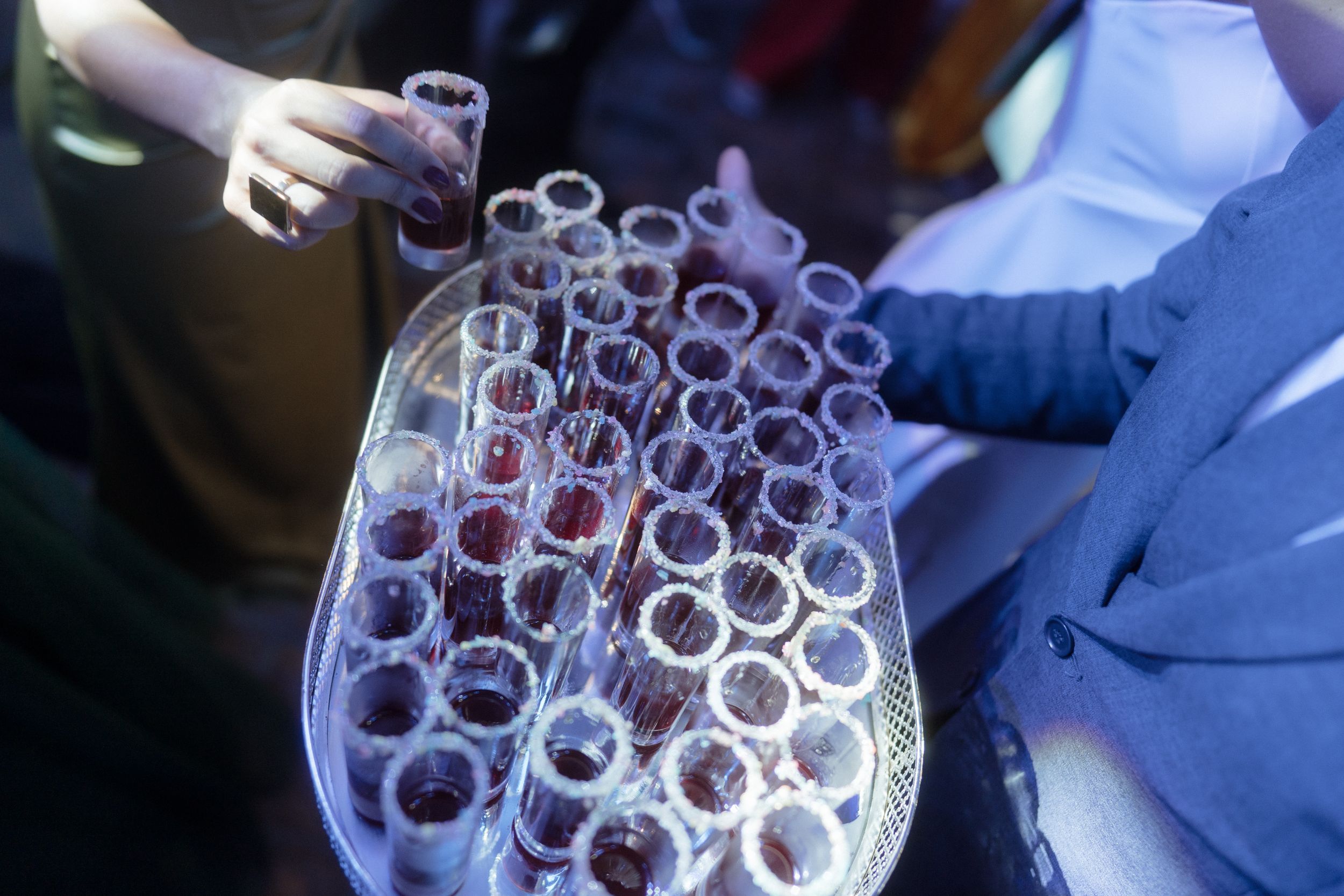 Tray of red cocktail shots arranged in neat rows at a party.