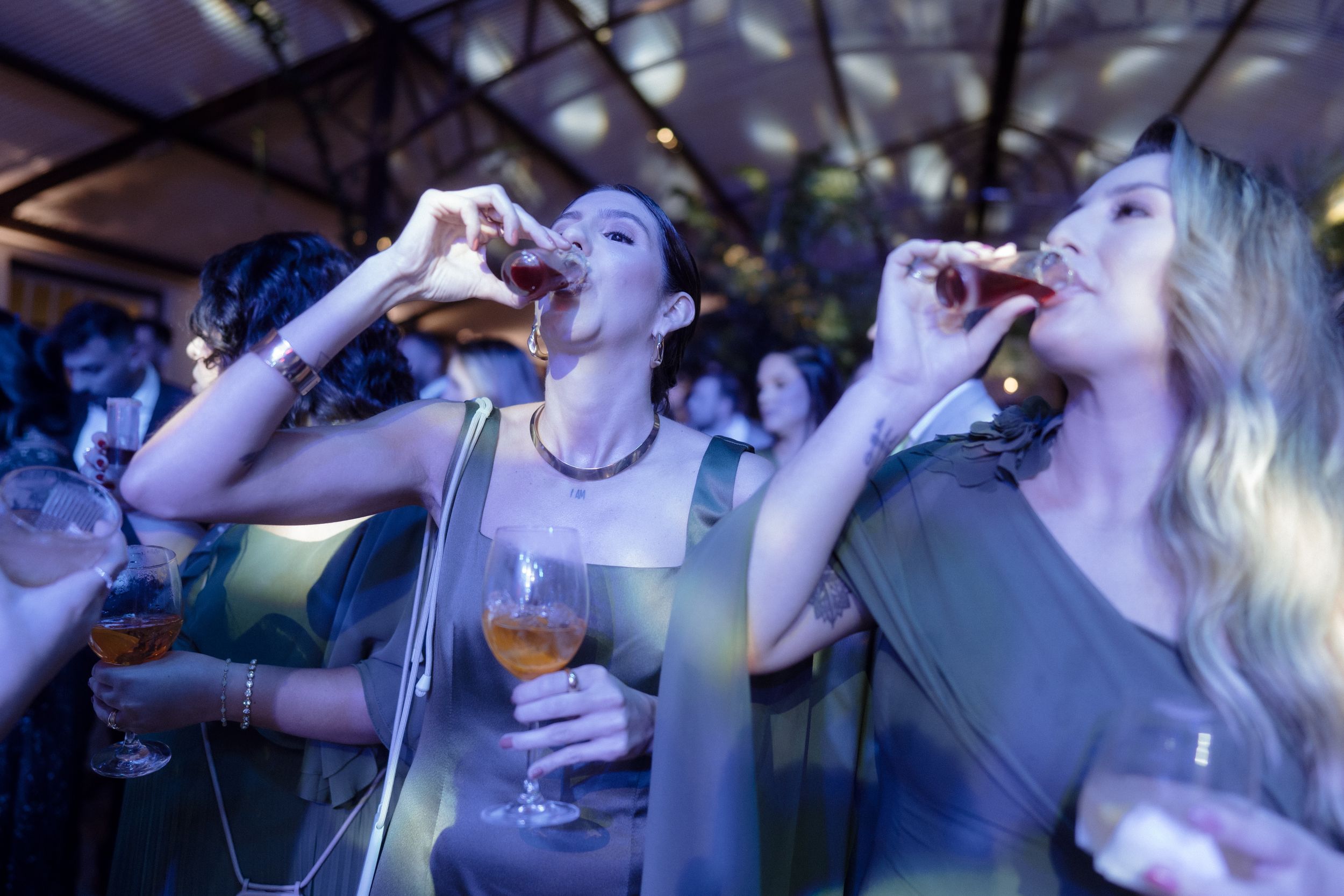 Guests enthusiastically taking shots together at a dimly lit party.