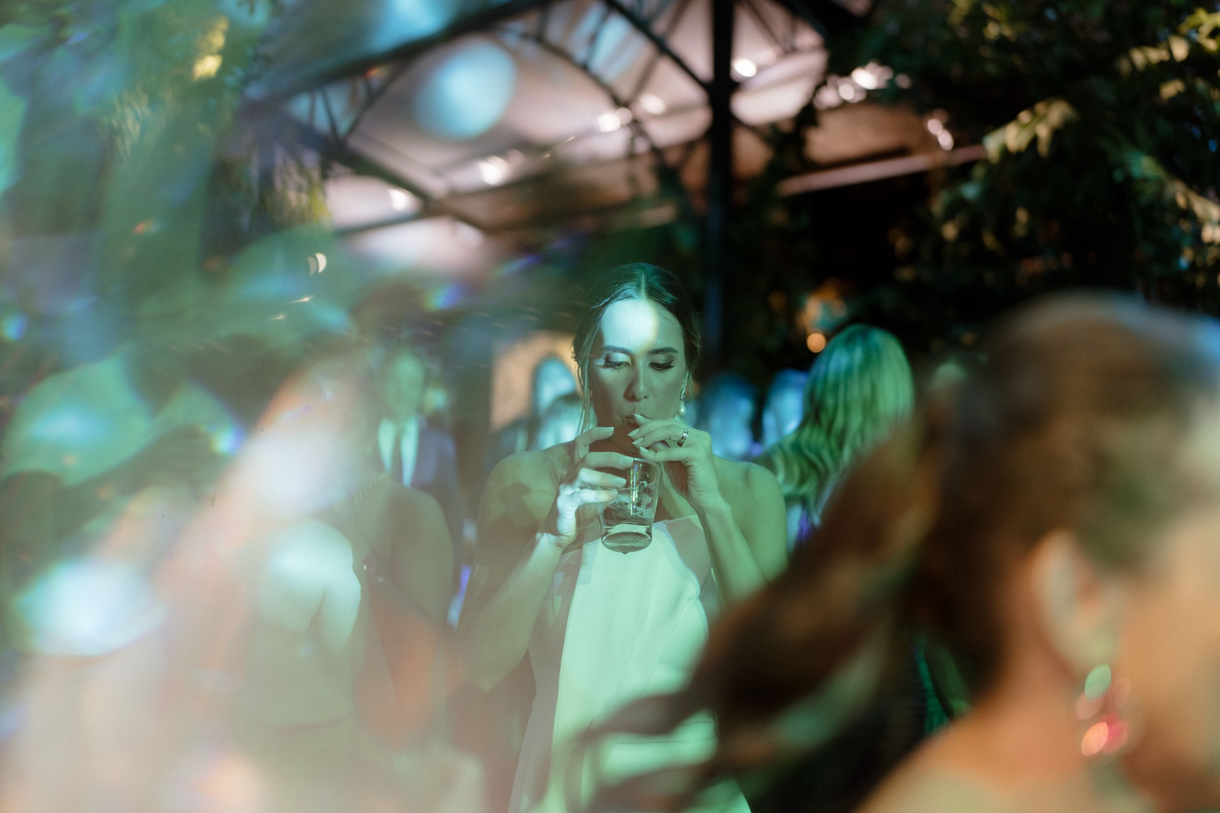 Partygoer using smartphone in a crowded venue with teal lighting effects.