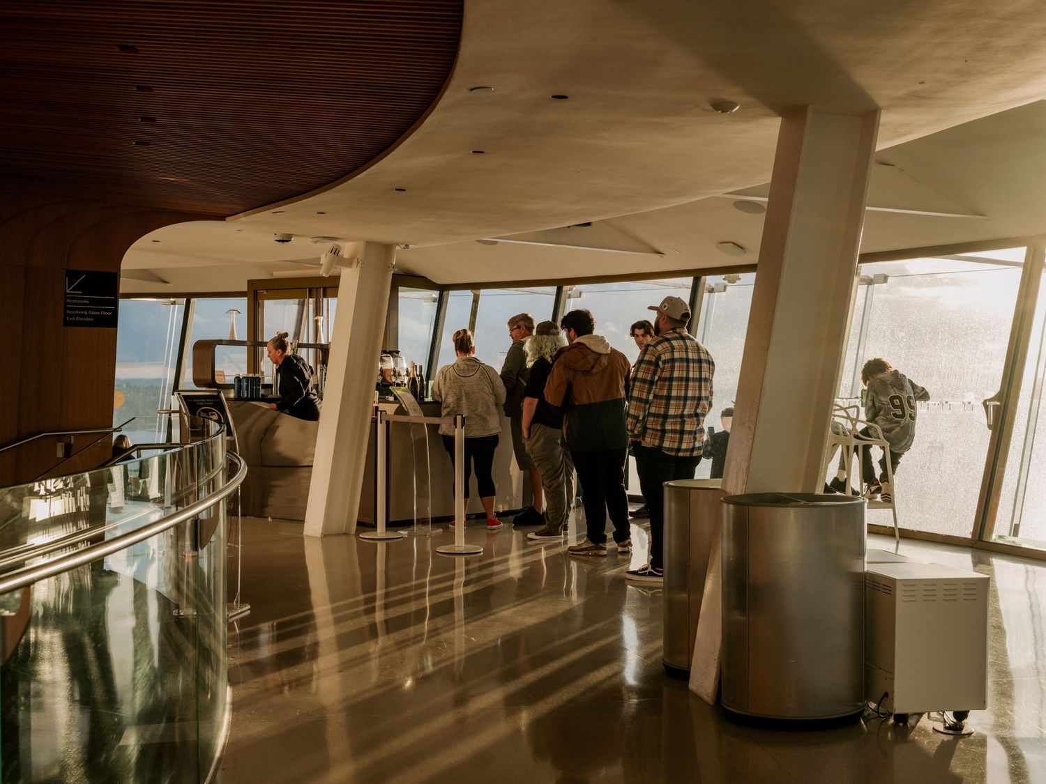 Visitors gather in an observation deck with curved glass windows offering panoramic views and modern interior architecture.