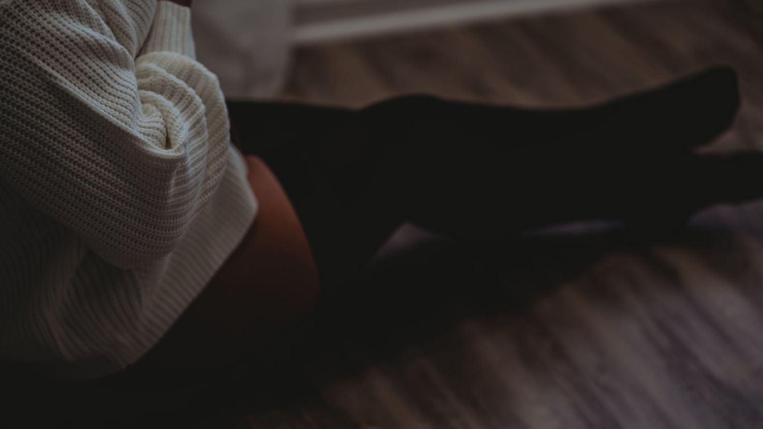 Dark atmospheric interior shot of a person sitting in moody lighting.