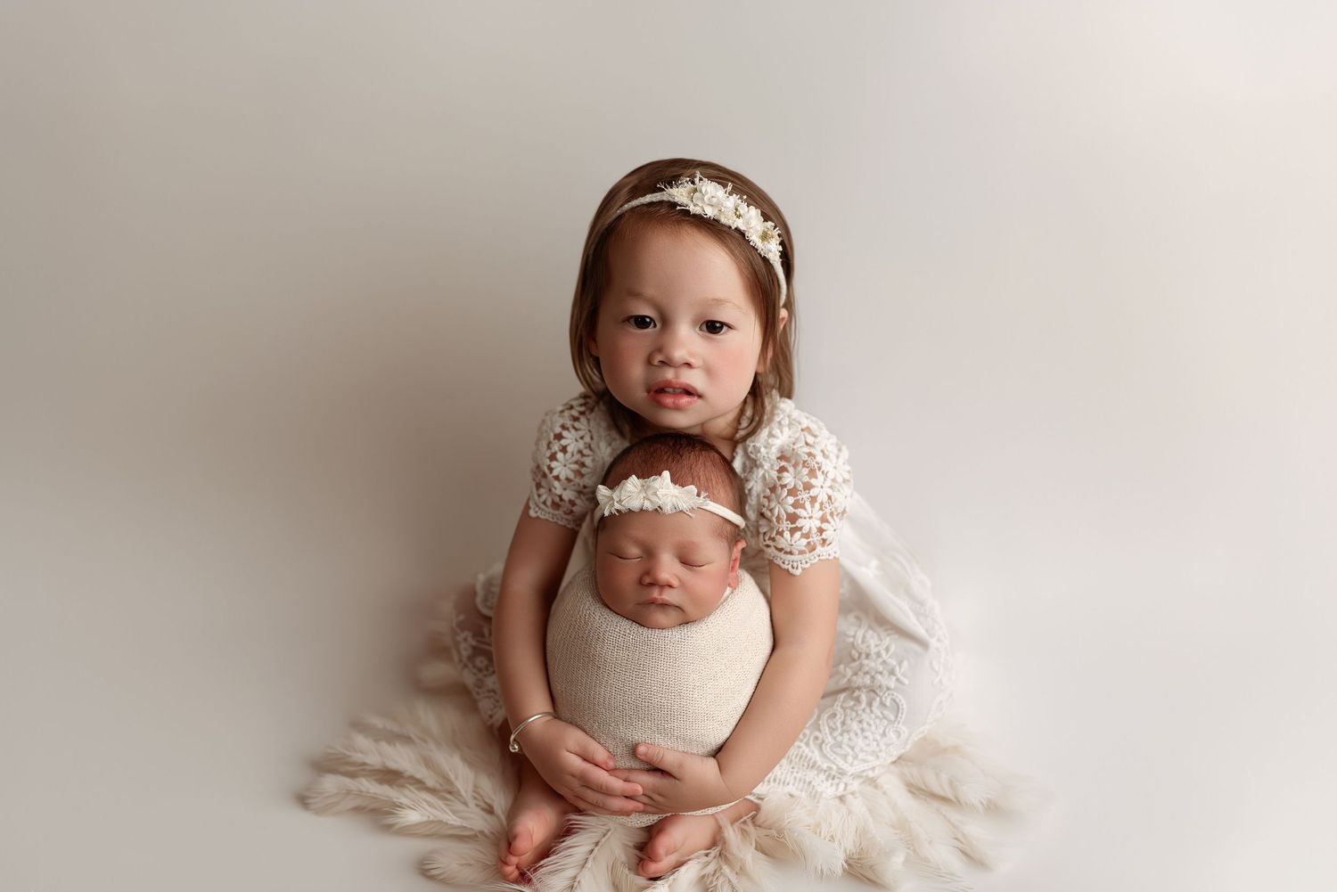 A sweet sibling portrait on a fluffy white rug during a professional newborn photo session. – newborn photographer Paloma Schell Houston TX