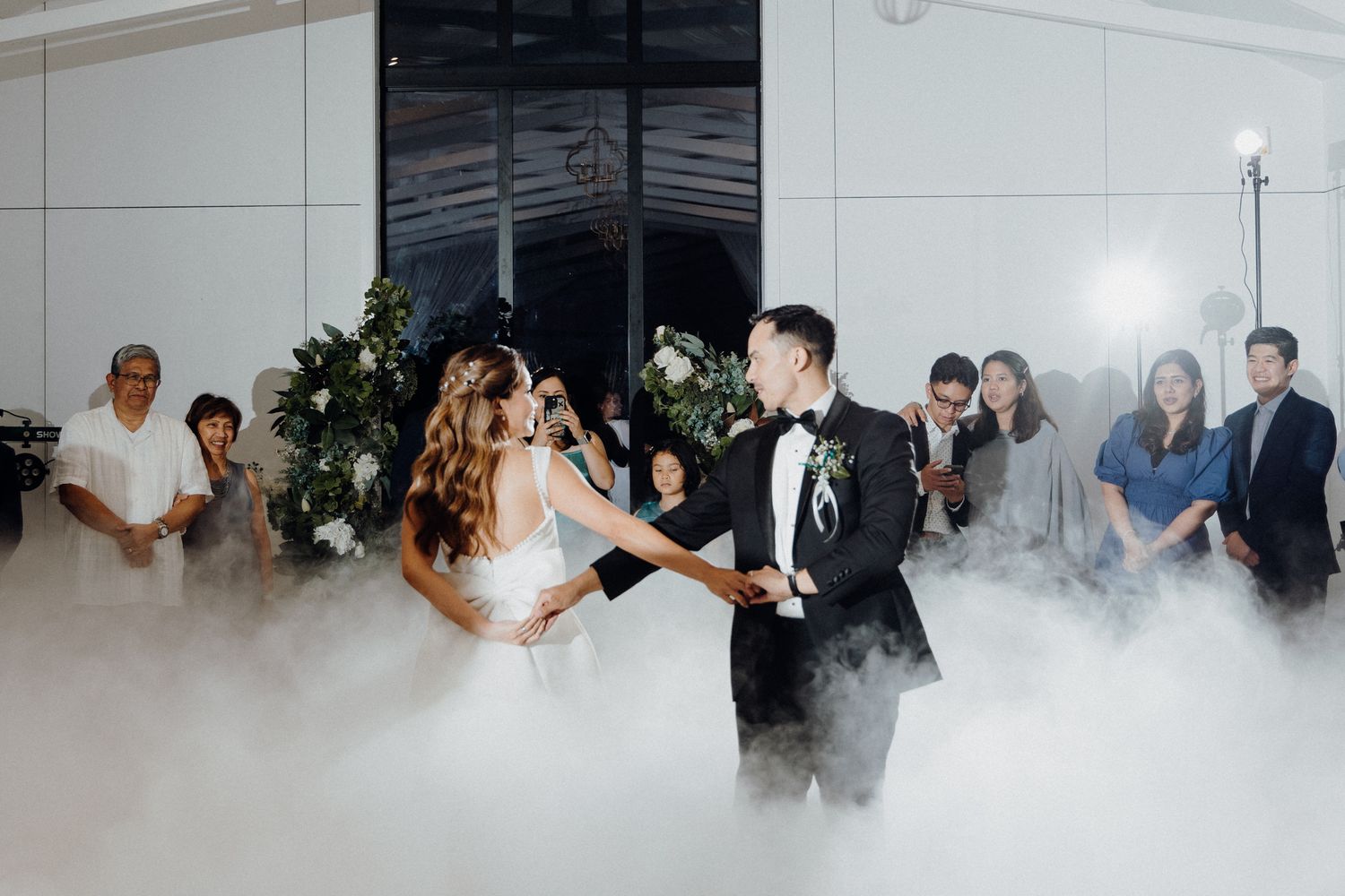 A couple shares their first dance surrounded by swirling fog effects captured by Apertured Media Auckland Wedding Photographer.