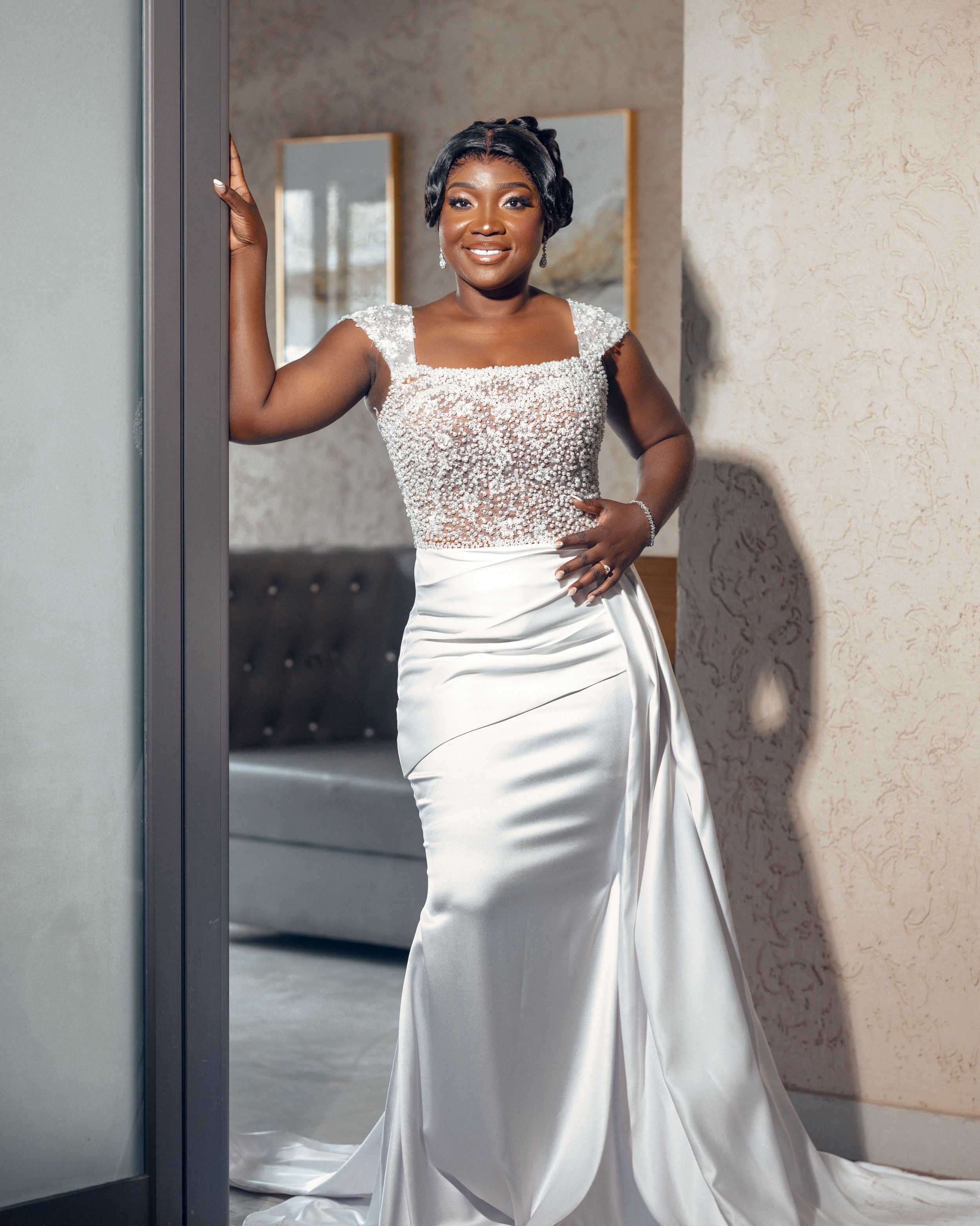 Elegant bride poses in form-fitting wedding gown with beaded top and silk skirt.