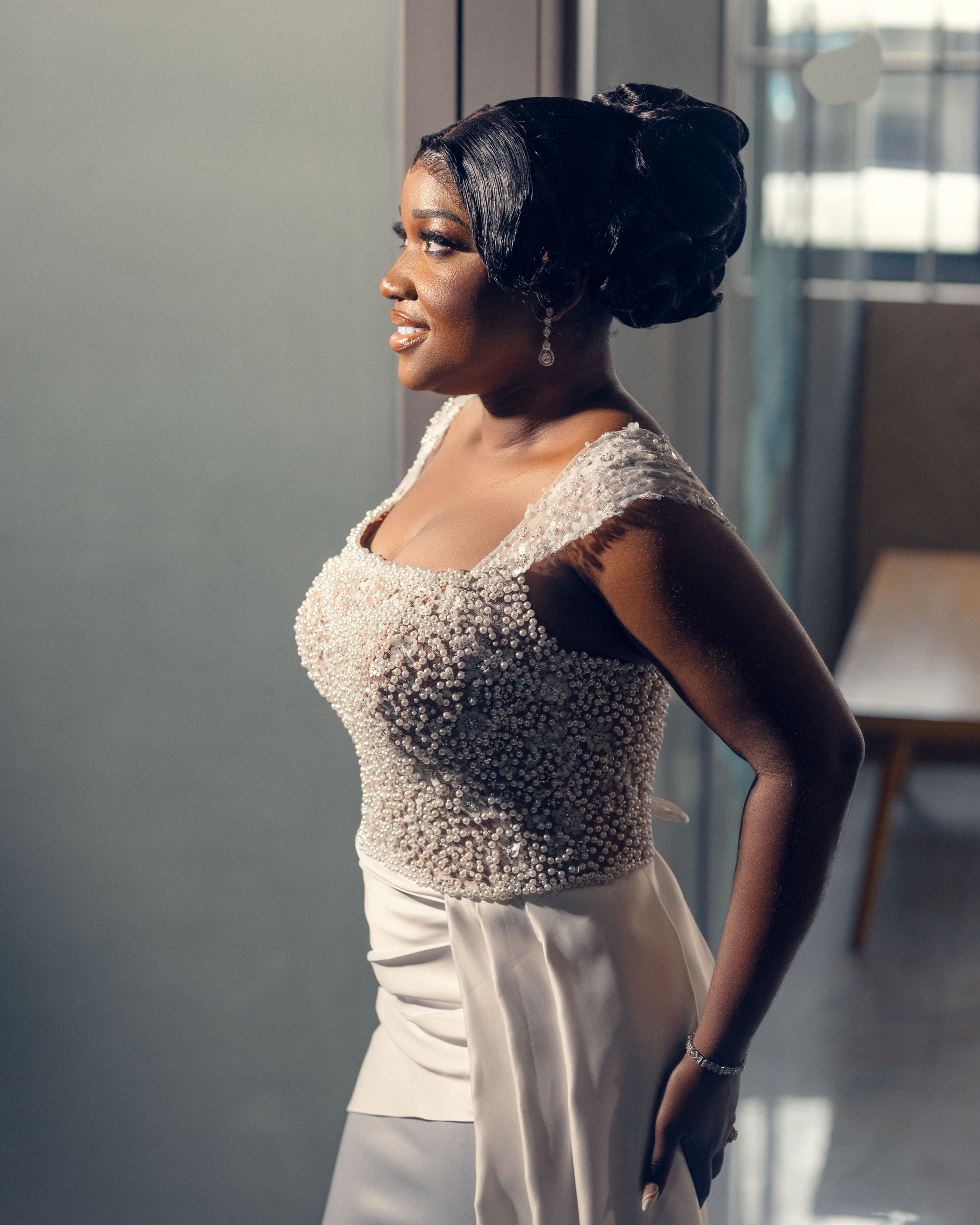 Side profile of bride in intricately beaded wedding dress with elegant updo.