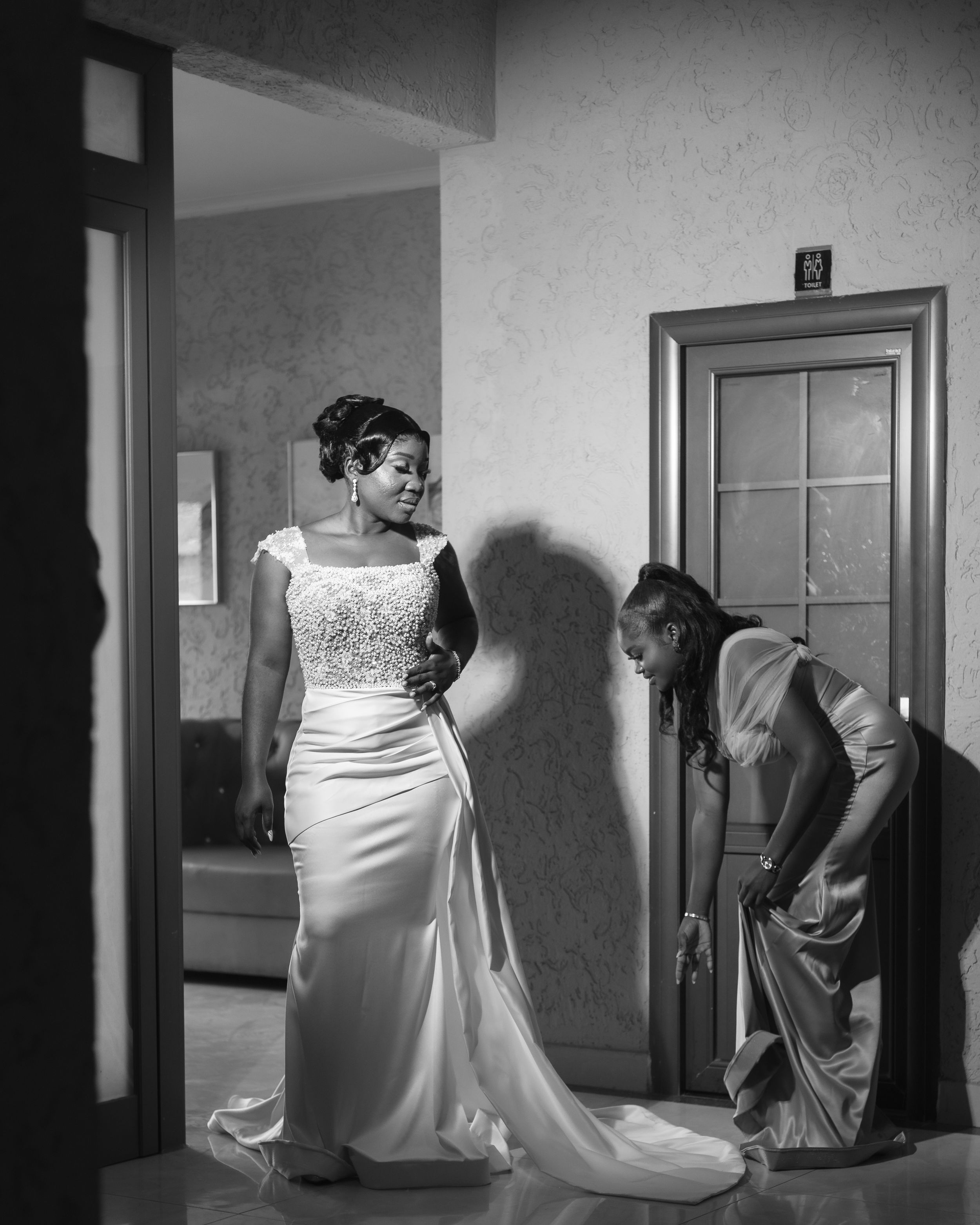 Wedding dress fitting moment captured in dramatic black and white photography.