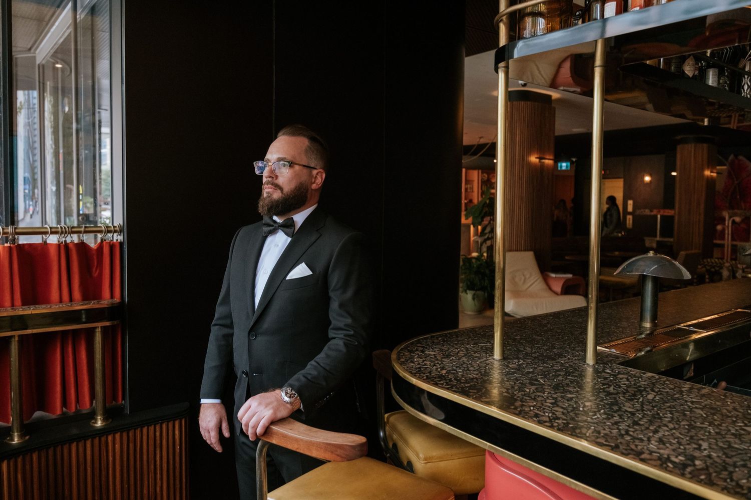 Elegant tuxedo portrait in dimly lit bar setting.