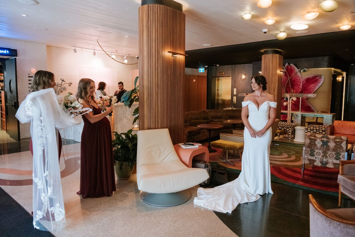 Wedding party gathering in modern hotel lobby with retro decor.