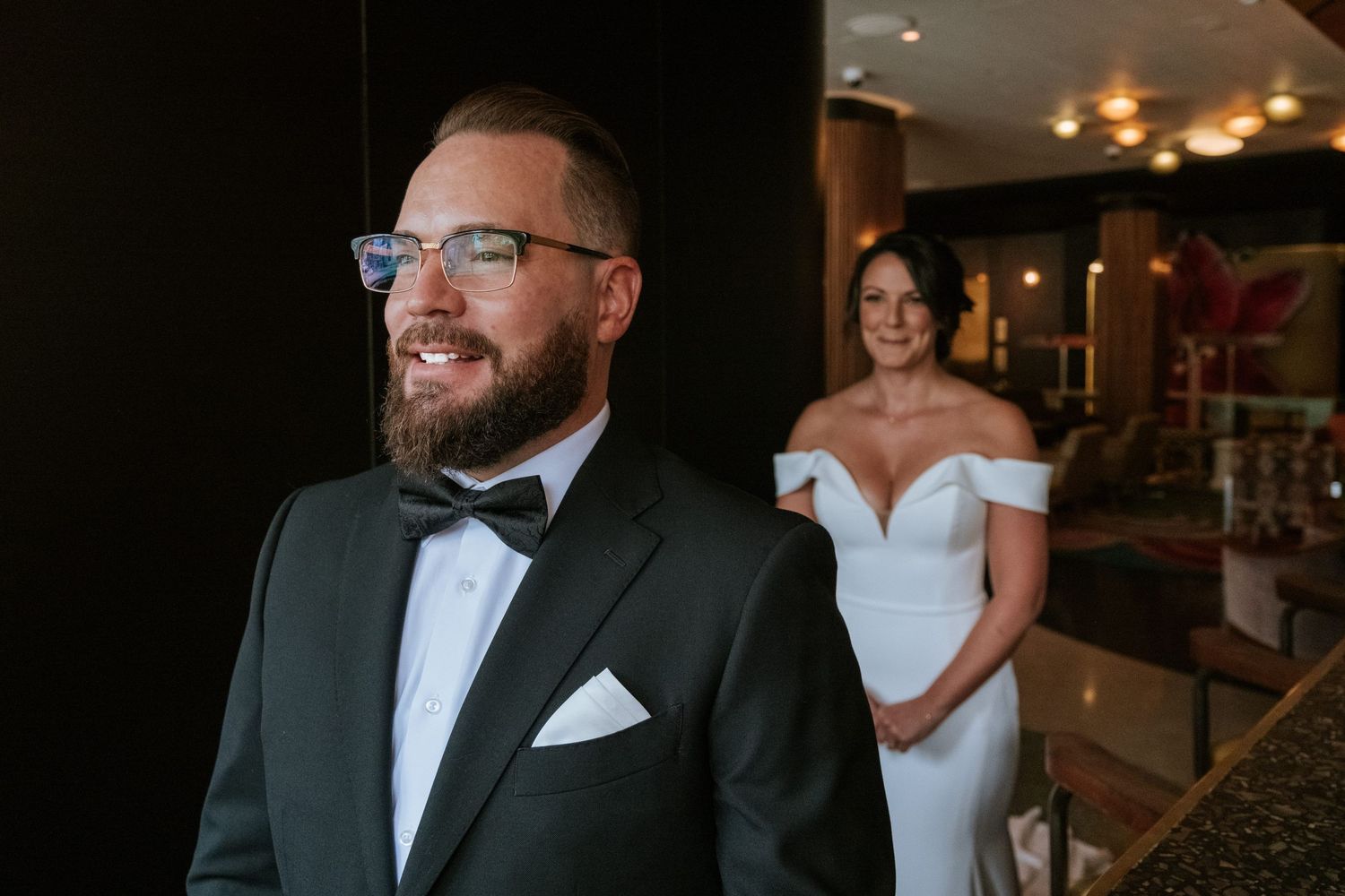 Elegant couple shares joyful moment in formal attire at upscale venue.