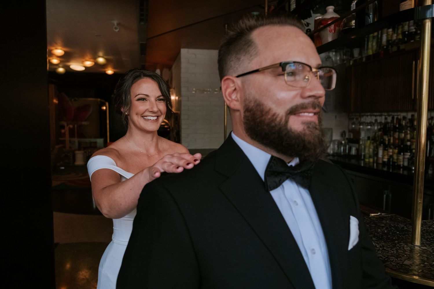 Couple shares an intimate first look moment at a dimly lit bar during their wedding celebration.