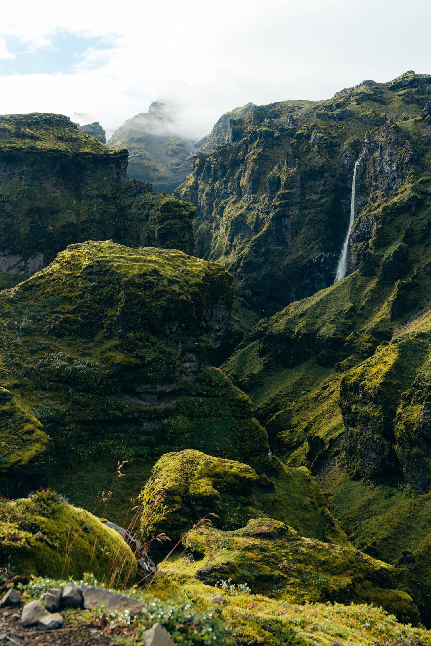 Panoramic view of Sani Pass in Lesotho showing dramatic mountain cliffs, winding roads and cascading waterfalls.