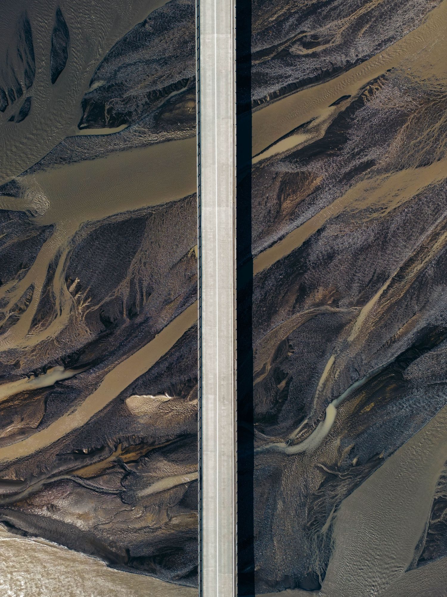 Aerial view of winding river patterns creating abstract shapes through mountainous desert terrain.