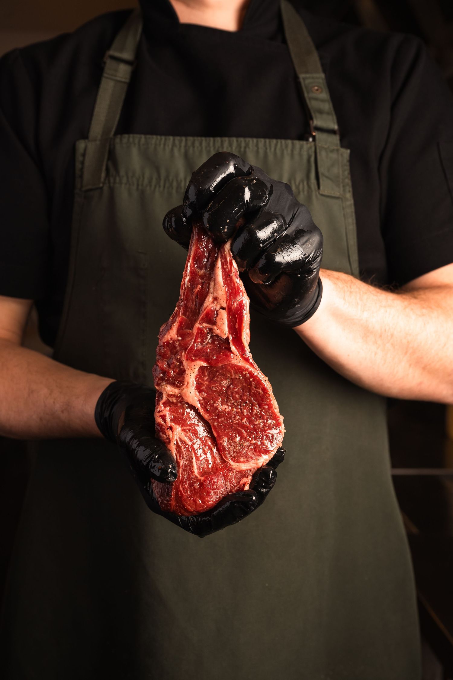 Restaurant branding photography featuring premium dry-aged steak prepared by chef in commercial kitchen