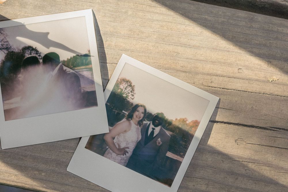 Polaroid wedding photos displayed on a wooden surface in natural sunlight.