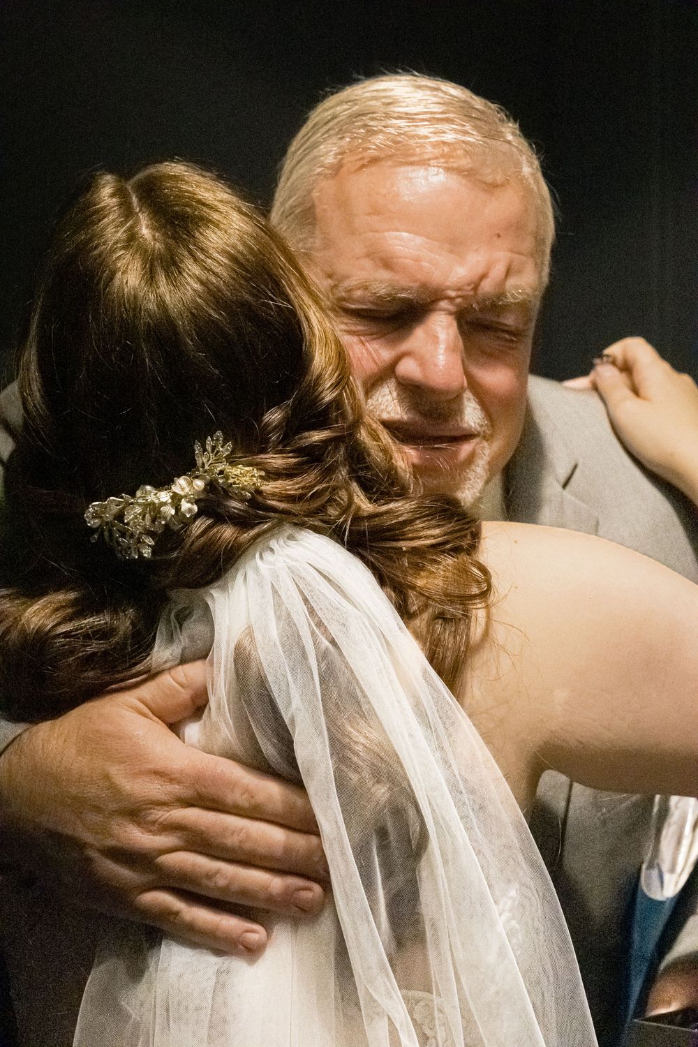 Emotional embrace captured during wedding celebration in dramatic lighting.