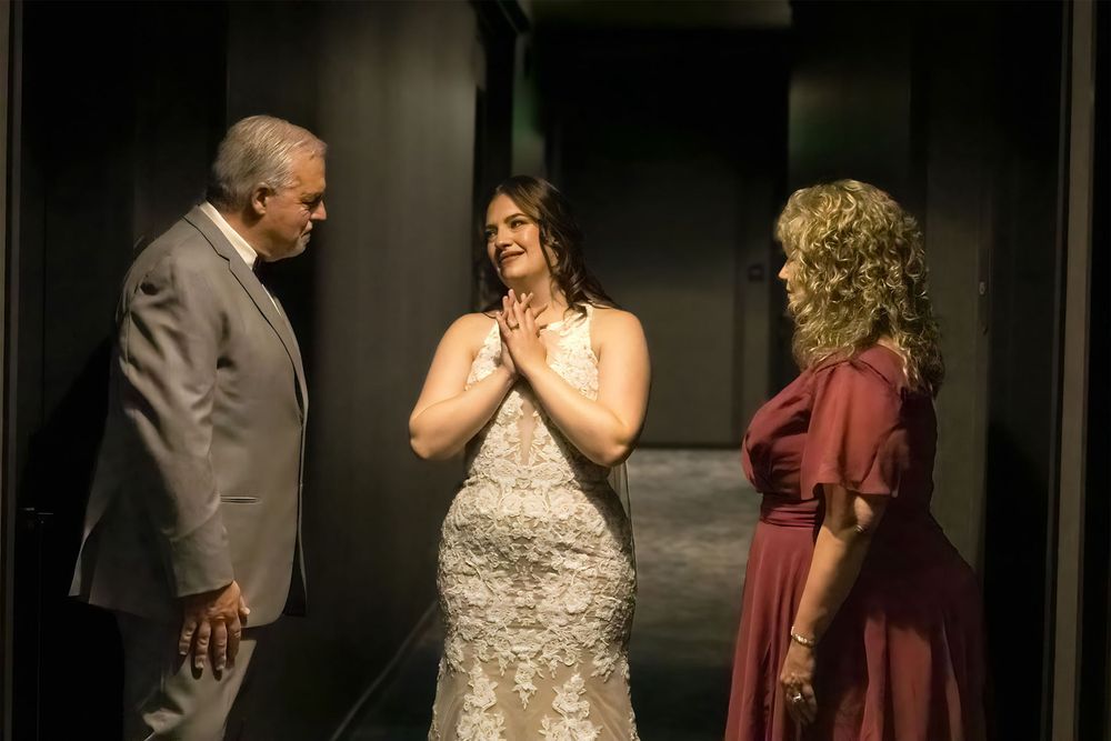 Emotional wedding moment shared between bride and family members in formal attire.