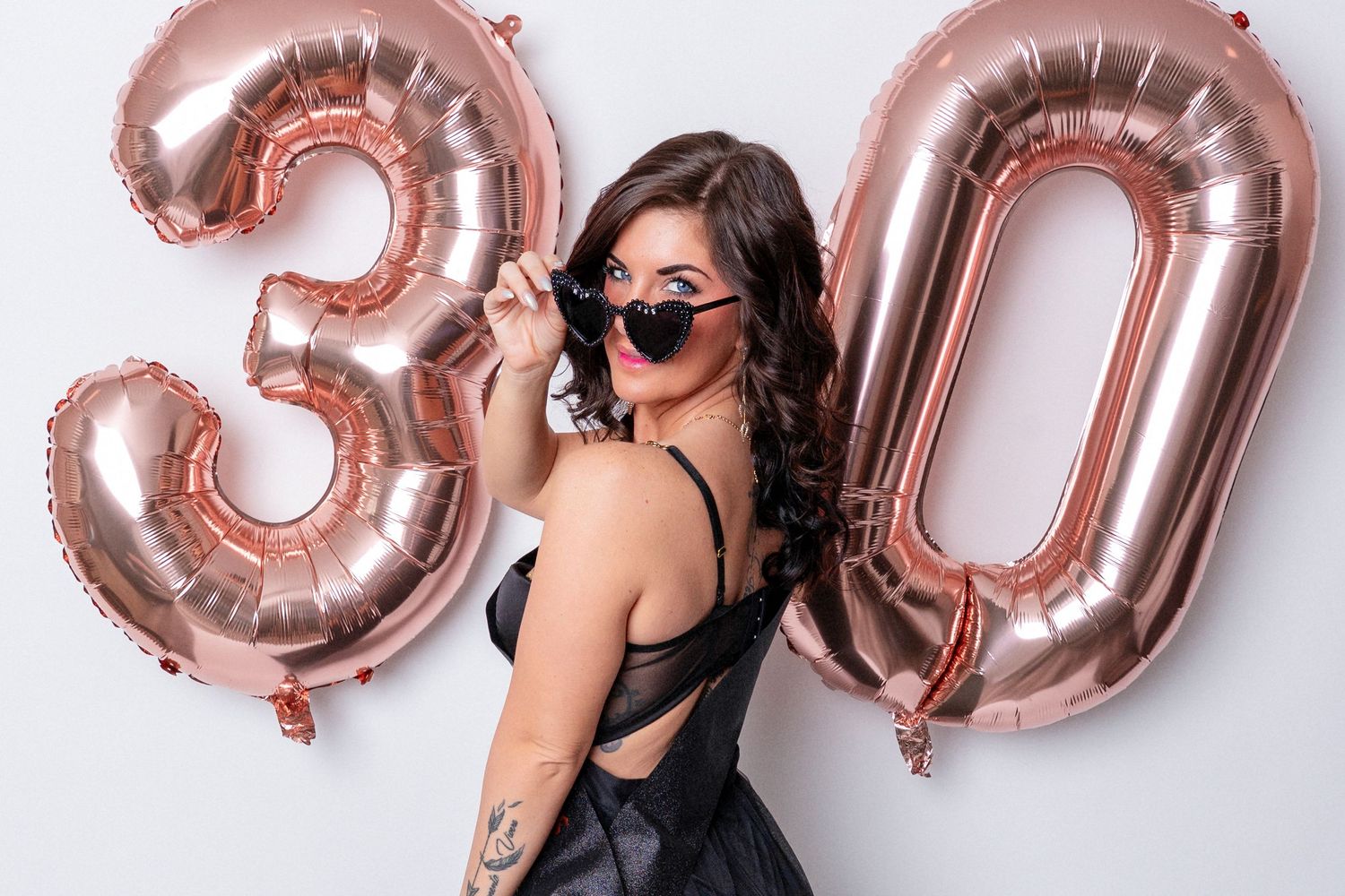 Photo of a woman from Knoxville posing with sunglasses and birthday balloons in East Tennessee portrait photographer's studio.
