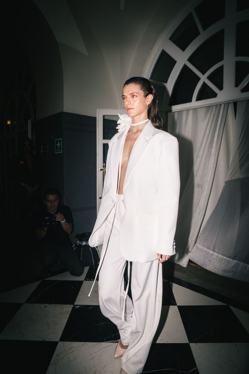 Model in flowing white outfit walking backstage corridor | BTS Fashion Photography by Dario Hudon-Verrelli, Le Café Studio