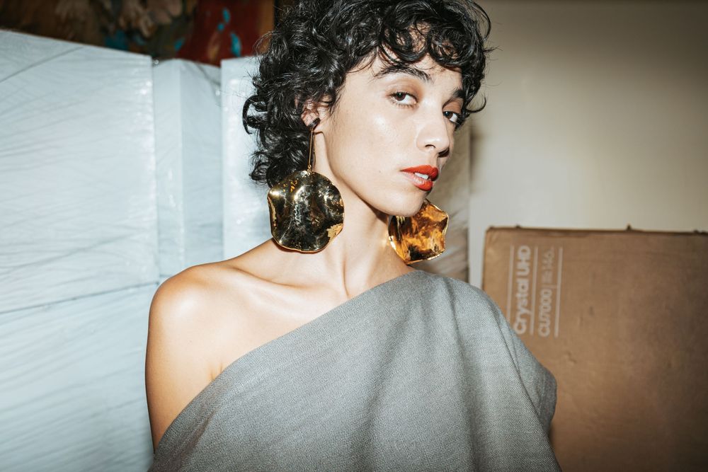 Portrait of model in grey off-shoulder look with bold earrings | Editorial Photography by Dario Hudon-Verrelli, Le Café Studio