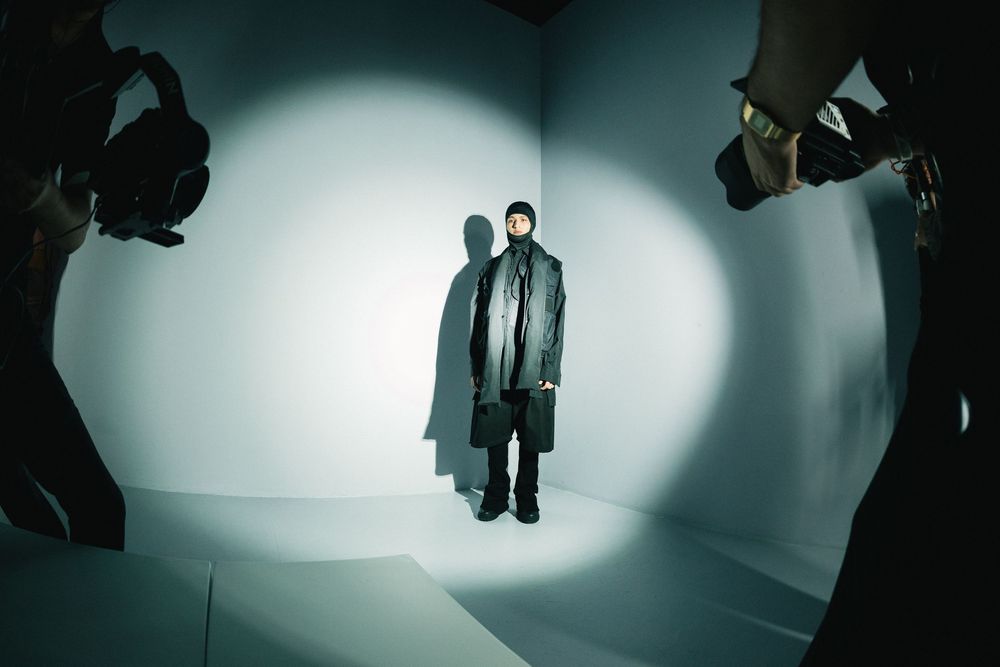 Model in long coat walking white runway with photographers in frame | Fashion Photography by Dario Hudon-Verrelli, Le Café Studio