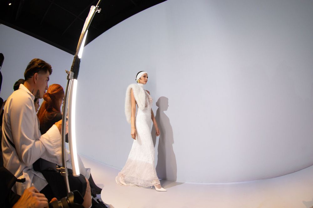 Model in elegant white gown walking runway with curved backdrop | Fashion Photography by Dario Hudon-Verrelli, Le Café Studio