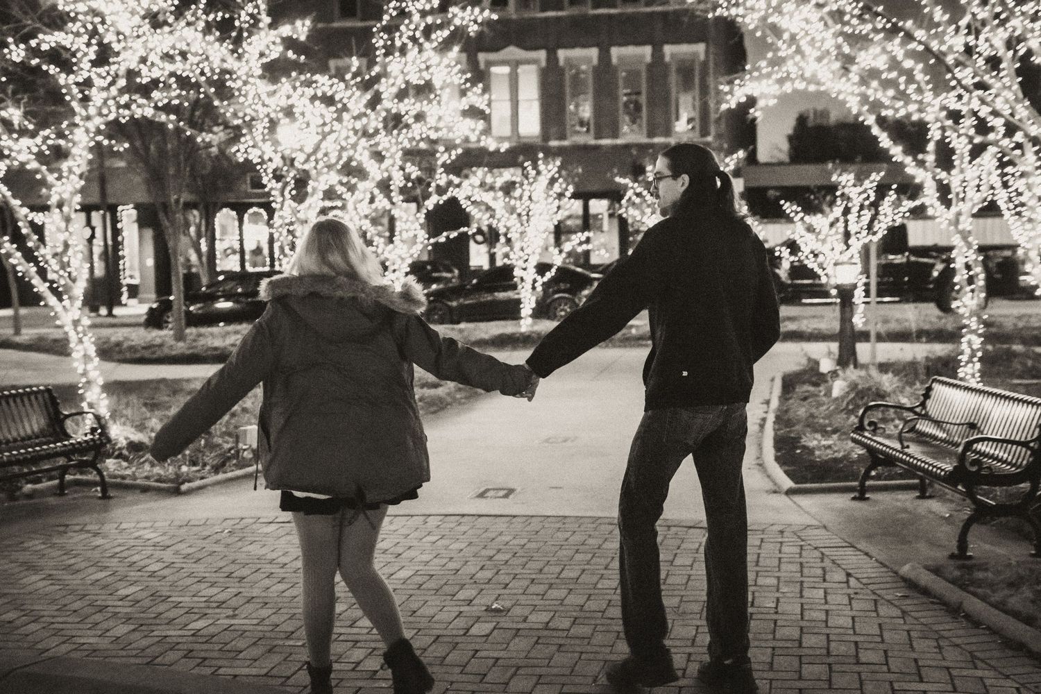 Couple strolling through Fountain Square Park in downtown Bowling Green, Kentucky under the Christmas lights