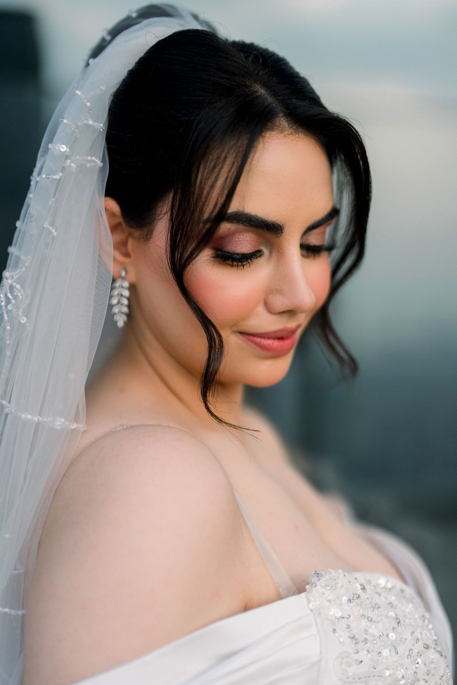 A bride in a white veil poses with soft lighting and natural makeup for romantic bridal portraits.