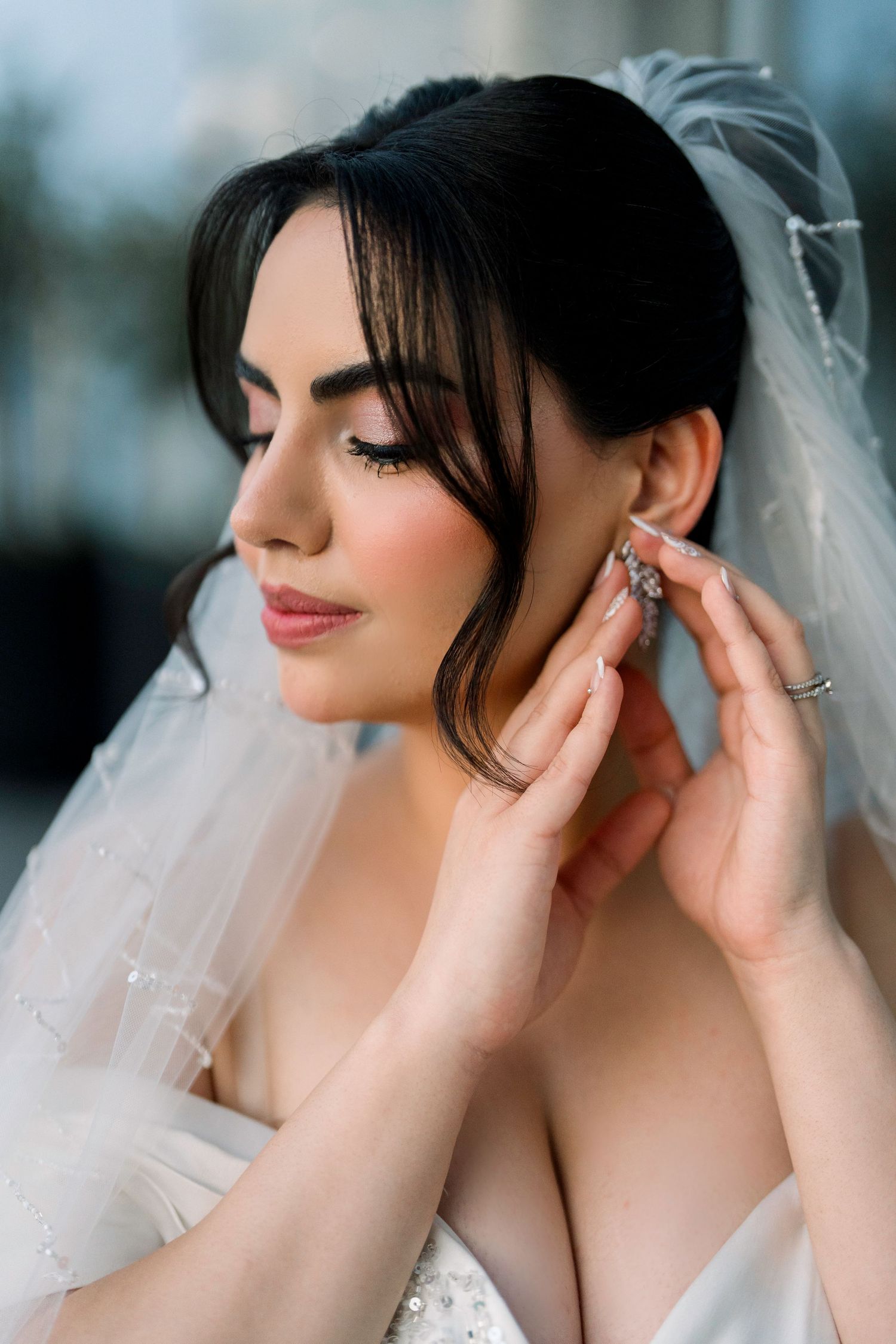 Close-up shots of a bride wearing a delicate white veil and elegant makeup in soft natural lighting.
