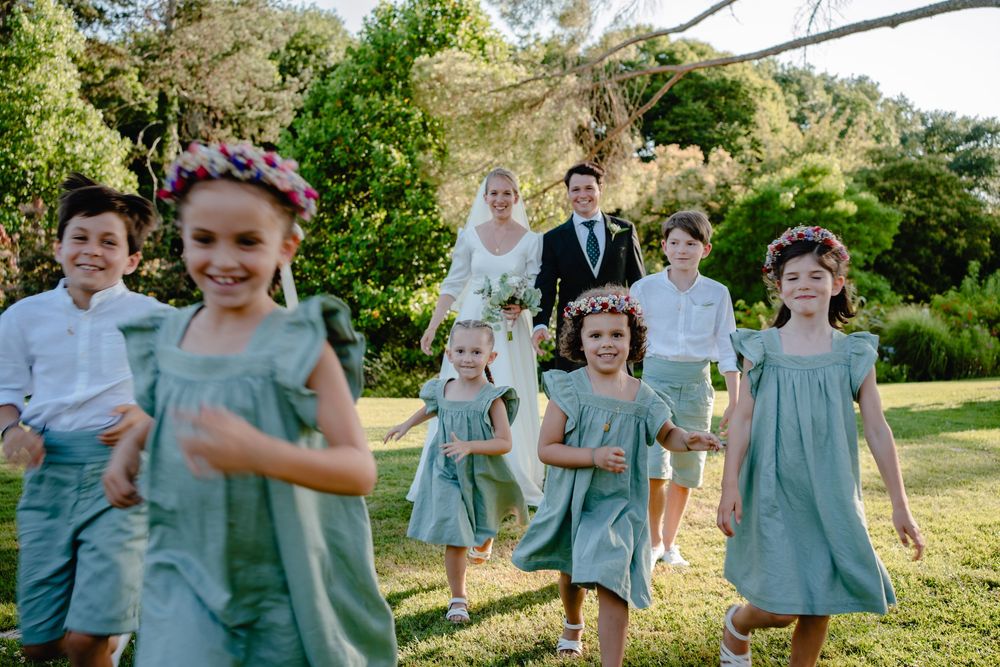 Wedding party in light blue dresses walking outdoors in a garden setting.